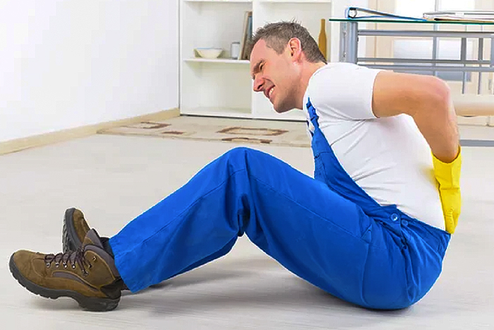 man in overalls suffering from a back injury